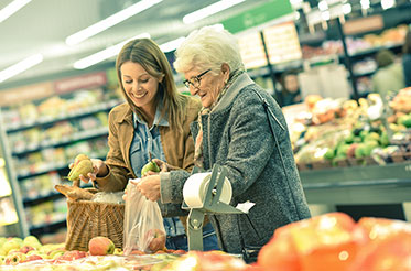 Nahaufnahme: Eine jüngere Frau hilft einer älteren Frau beim Einkaufen