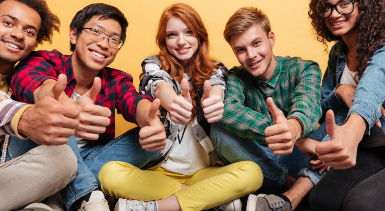 Eine Gruppe junger Menschen, sitzend und den Daumen nach oben zeigend