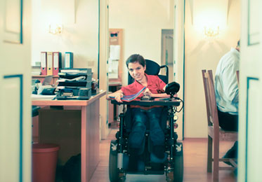 Junge Frau mit Rollstuhl im Büro.