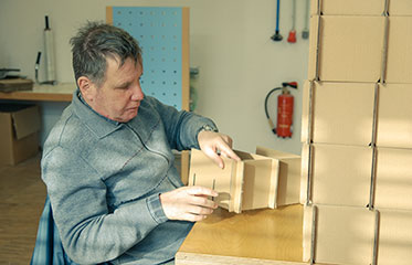 Ein Mann beim Zusammenbauen eines Holzkastens.