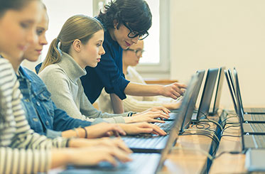 Nahaufnahme: Eine Lehrerin arbeitet mit Schülerinnen an Laptops