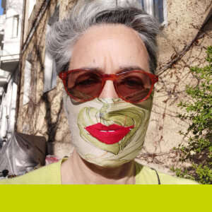Irina Wanka trägt eine Sonnenbrille und eine Maske mit geschminkten Lippen darauf.