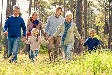 Gruppe von Menschen unterschiedlicher Generationen beim gemeinsamen Spaziergang im Wald.