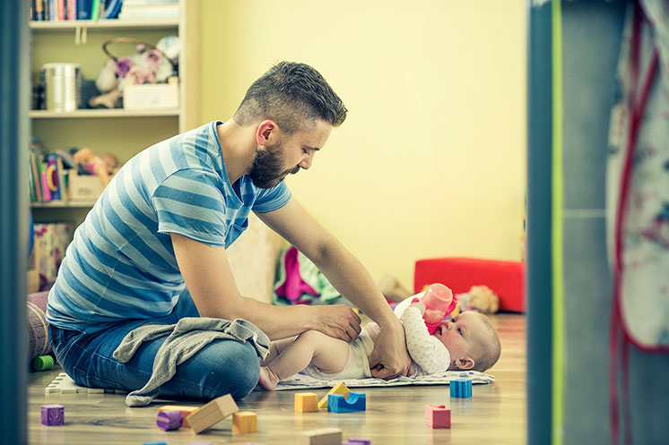Organisation des Familienalltags Mann mit Baby beim Windelnwechseln