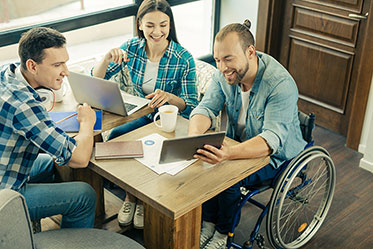Vergrößerungsansichten für Bild: Drei Personen in einem lebhaften Gespräch. Eine von ihnen sitzt im Rollstuhl.