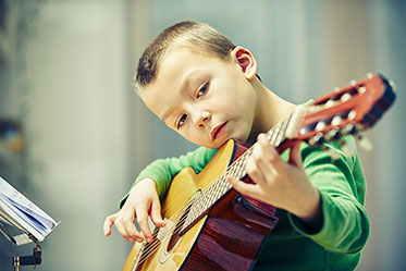 Nahaufnahme: Ein Junge spielt auf einer Gitarre