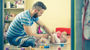 Vergrößerungsansichten für Bild: Junger Vater wickelt Baby.