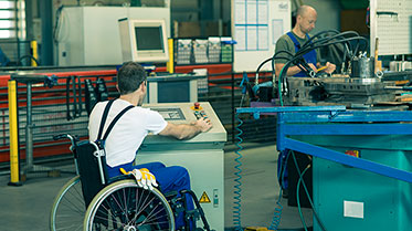 Mann im Rollstuhl arbeitet an Maschine