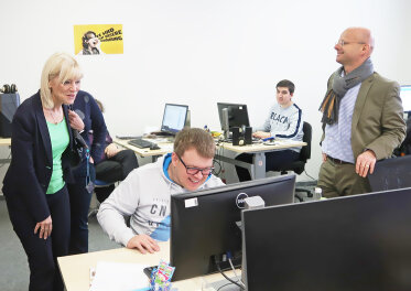 Staatssekretärin Carolina Trautner steht hinter einem Mann, der auf einen PC blickt.