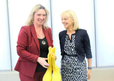 Bauministerin Kerstin Schreyer hält das Abschiedsgeschenk von Carolina Trautner in Händen: gelbe Gummistiefel.