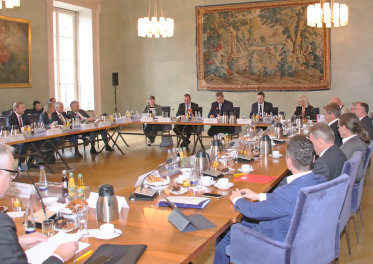 Staatssekretärin Carolina Trautner mit mehreren Personen an Tischen sitzend. 