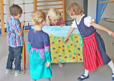 Staatssekretärin Carolina Trautner mit Kindern, die auf ein Bild zeigen. 