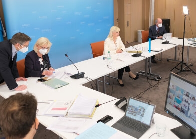 Auf dem Bild sind 5 Personen zu sehen. Darunter Staatsministerin Carolina Trautner sitzend an einem weißen Tisch mit Mikrofon.
