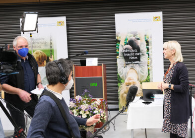 Sozialministerin Carolina Trautner vor einer Kamera stehend.