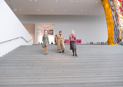 Auf dem Bild sind drei Personen zu sehen, die eine große Betontreppe heruntergehen. Das Bild ist von unten fotografiert.