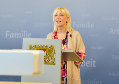 Auf dem Bild ist Sozialministerin Carolina Trautner an einem Rednerpult zu sehen. 