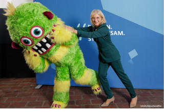 Das Foto zeigt Staatsministerin Ulrike Scharf mit dem Rollenmonster