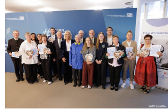 Das Foto zeigt Bayerns Sozialministerin Ulrike Scharf mit den ehrenamtlich Engagierten, die den Ehrenamtsnachweis verliehen bekommen haben