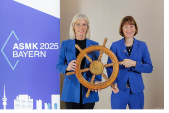 Das symbolische Steuerrad des ASMK-Vorsitzes übergab die bayerische Sozialministerin Ulrike Scharf (links) an Heike Hofmann aus Hessen, die 2026 den Vorsitz innehat.