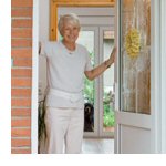 Ältere Dame steht lächelnd in geöffneter Eingangstür