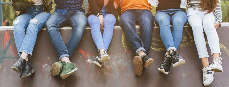 Bild: Zu sehen ist eine Gruppe Jugendliche, die mit verschränkten Beinen auf dem oberen Rand einer Halfpipe sitzen