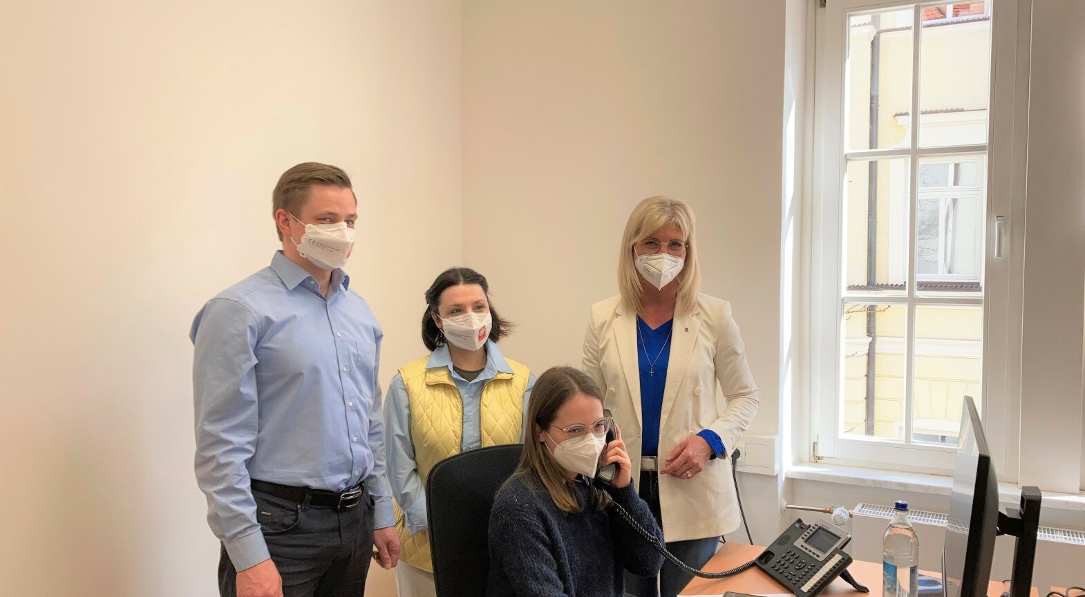 Das Foto zeigt Bayerns Sozialministerin Ulrike Scharf mit den Mitarbeiterinnen und Mitarbeitern des Hilfetelefons