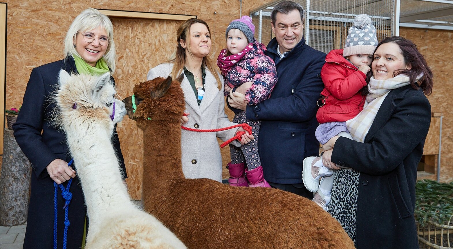Das Foto zeigt Ministerpräsident Dr. Markus Söder und Familienministerin Ulrike Scharf mit Kinder der Kita Kleine Heimat und Alpakas