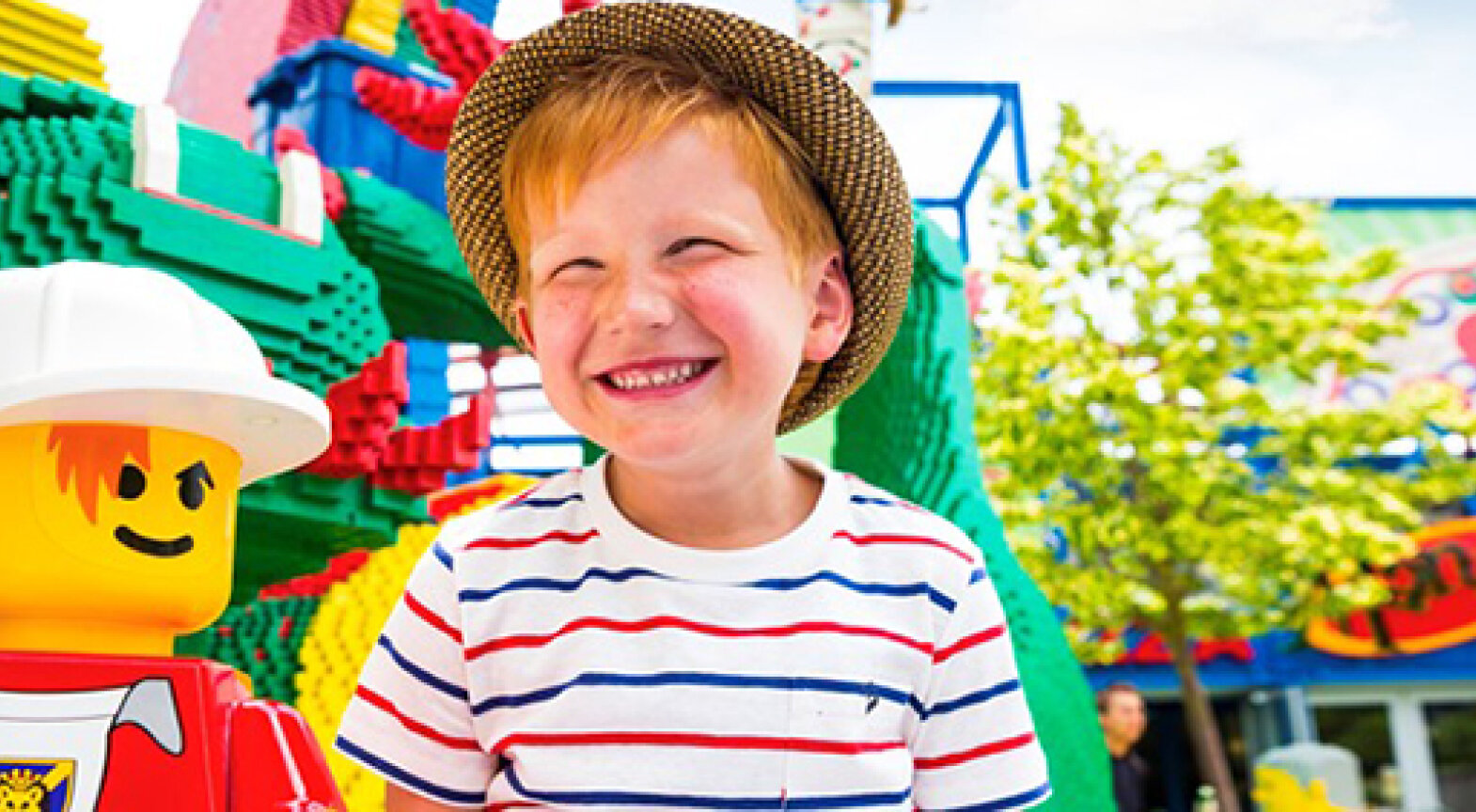 Das Foto zeigt ein Kind im Legoland neben einer Figur