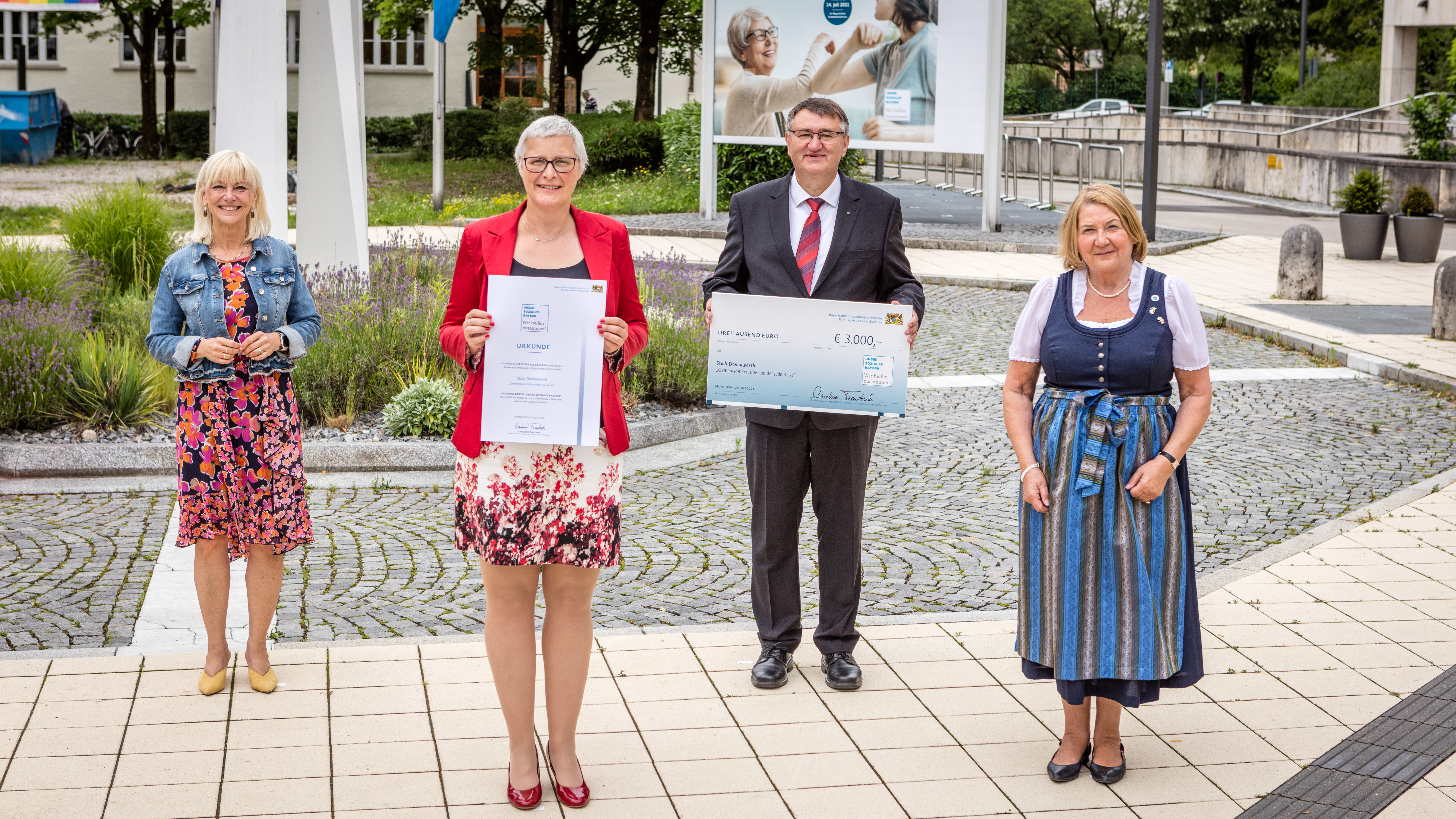Die ehemalige Staatsministerin Carolina Trautner steht neben drei Preisträgerinnen und einem Preisträger des Gewinnerprojekts „Gemeinsamkeit überwindet jede Krise“ der Stadt Donauwörth. Eine von ihnen hält eine Urkunde in den Händen, einer einen Scheck.  