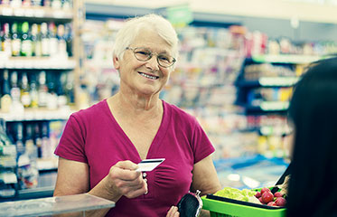 Im Geschäft: Lächelnde ältere Frau beim Bezahlen mit EC-Karte