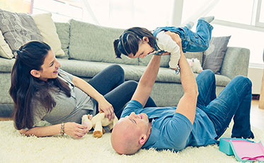 Vergrößerungsansichten für Bild: Junges Paar liegt auf dem Boden und spielt mit dem Kind.