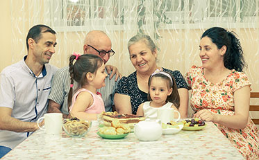 Vergrößerungsansichten für Bild: Familie unterschiedlicher Generationen beim gemeinsamen Essen am Tisch.