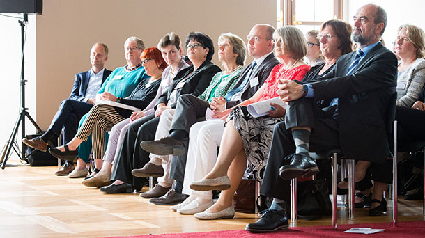 Gruppenfoto: Die erste Stuhlreihe der Podiumsveranstaltung samt Teilnehmer und Moderatoren